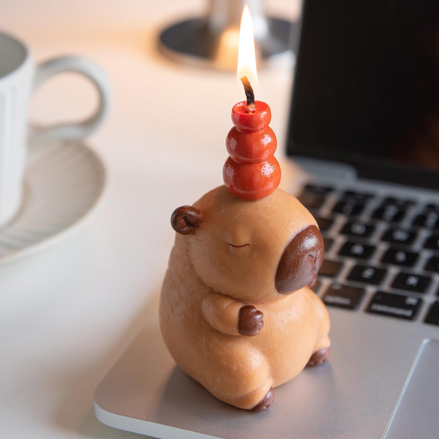 MrsCapybara capybara birthday candle lit on laptop keyboard near coffee cup