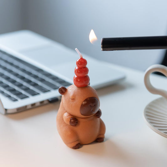 MrsCapybara capybara birthday candle lit on desk near coffee cup and laptop