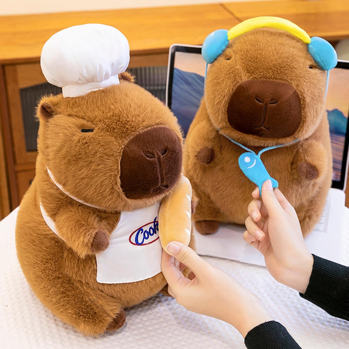 capybara chef plush wearing a white chef hat and apron holding a bread roll
