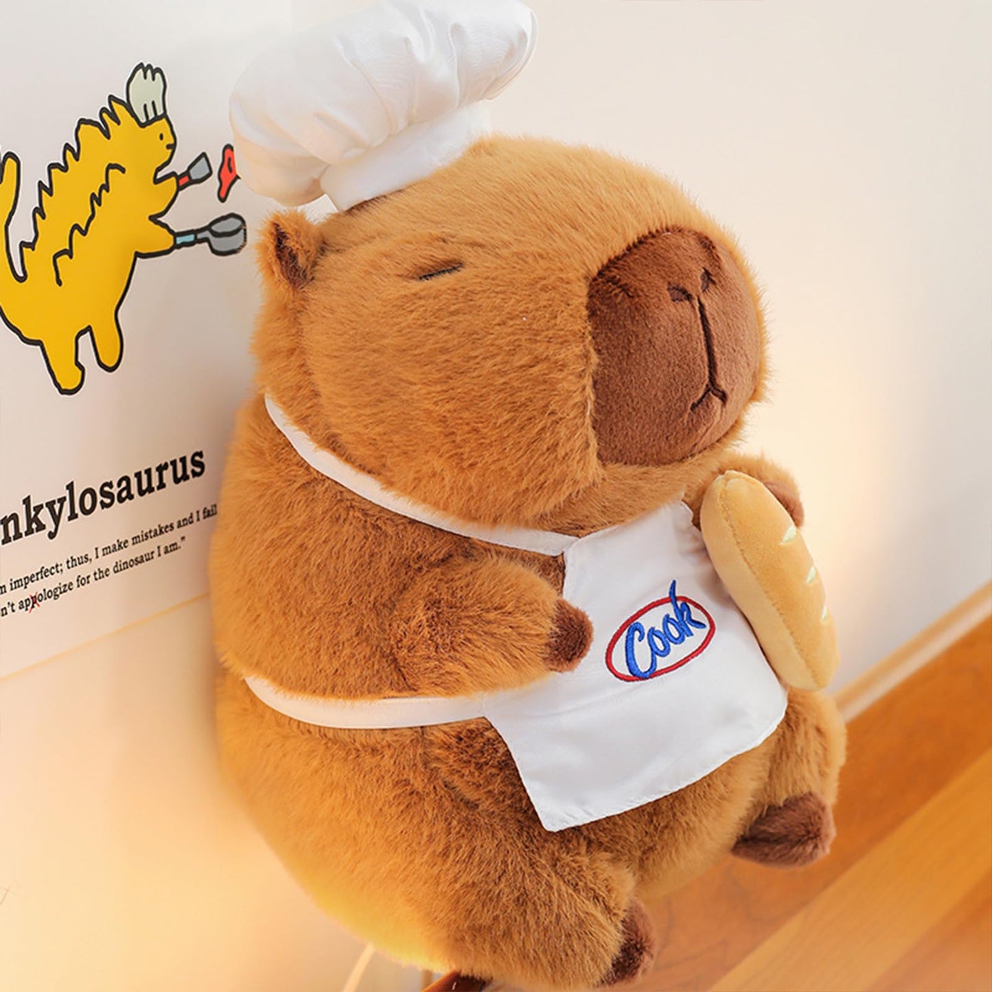 capybara chef plush wearing a white chef hat and apron holding a baguette bread toy