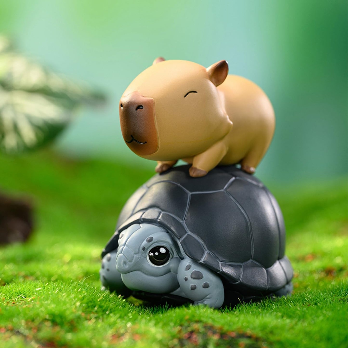 Capybara Cute Cake Toppers showing a smiling capybara figure sitting on a gray turtle on green grass