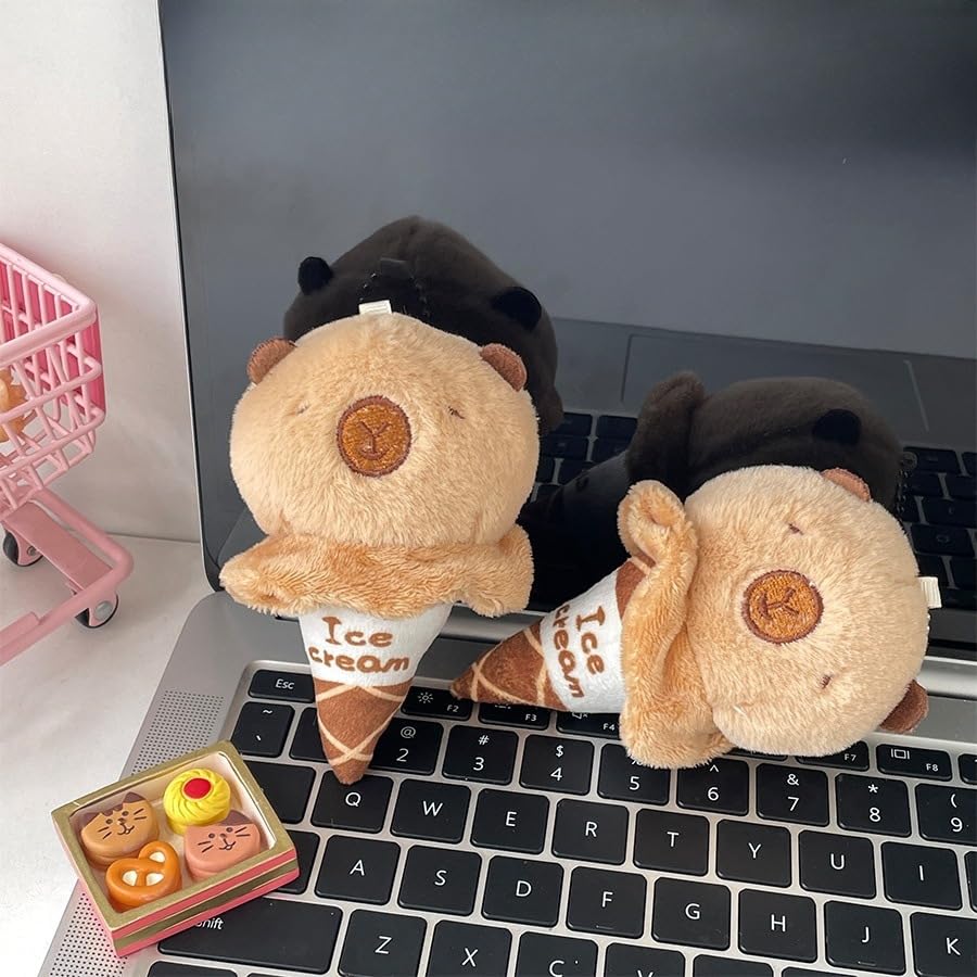 capybara ice cream keychain plush toy in light brown sitting on laptop keyboard