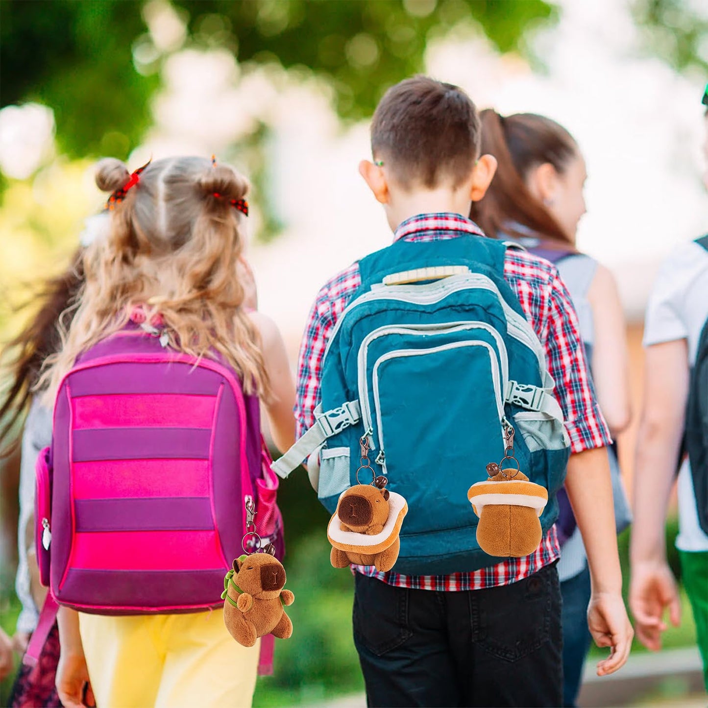 Children wearing backpacks with capybara keychain set hanging from the zippers outdoors