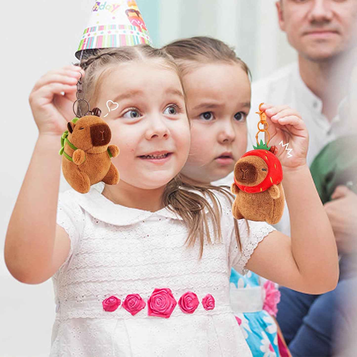 Children holding cute plush capybara keychain set with fruit costumes at a birthday party