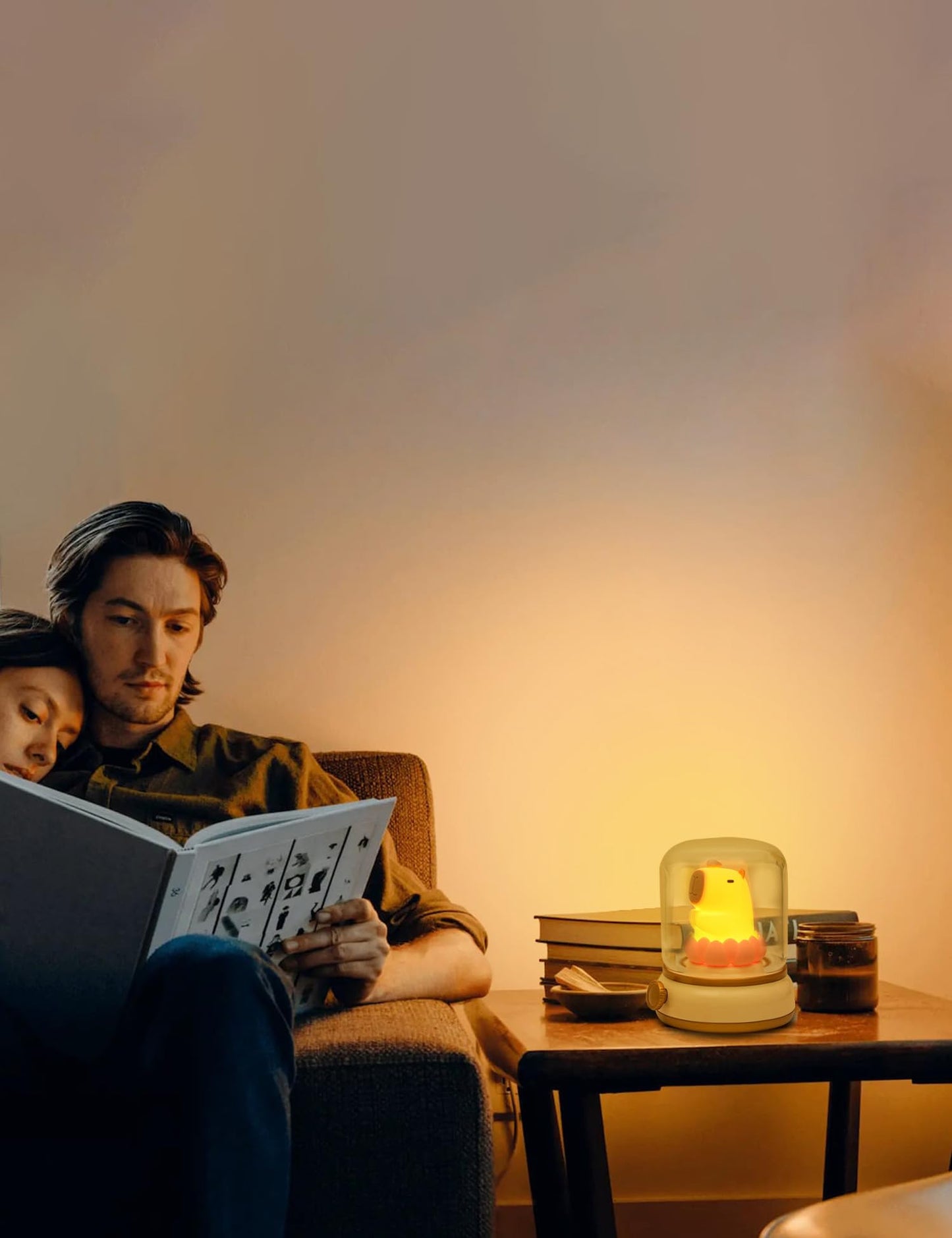 Warm glowing capybara night light on a table beside a man and child reading a book on the couch