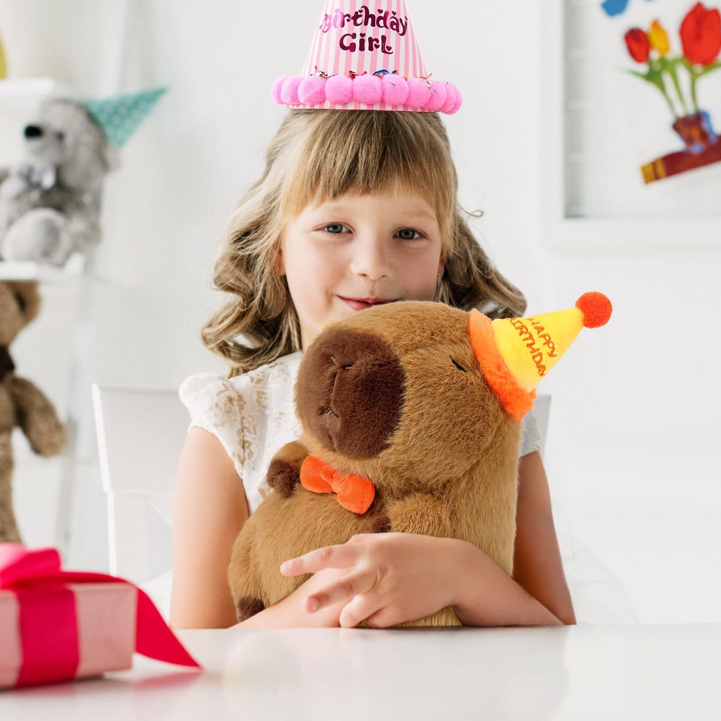 Girl holding capybara pillow plush wearing a birthday party hat and smiling indoors