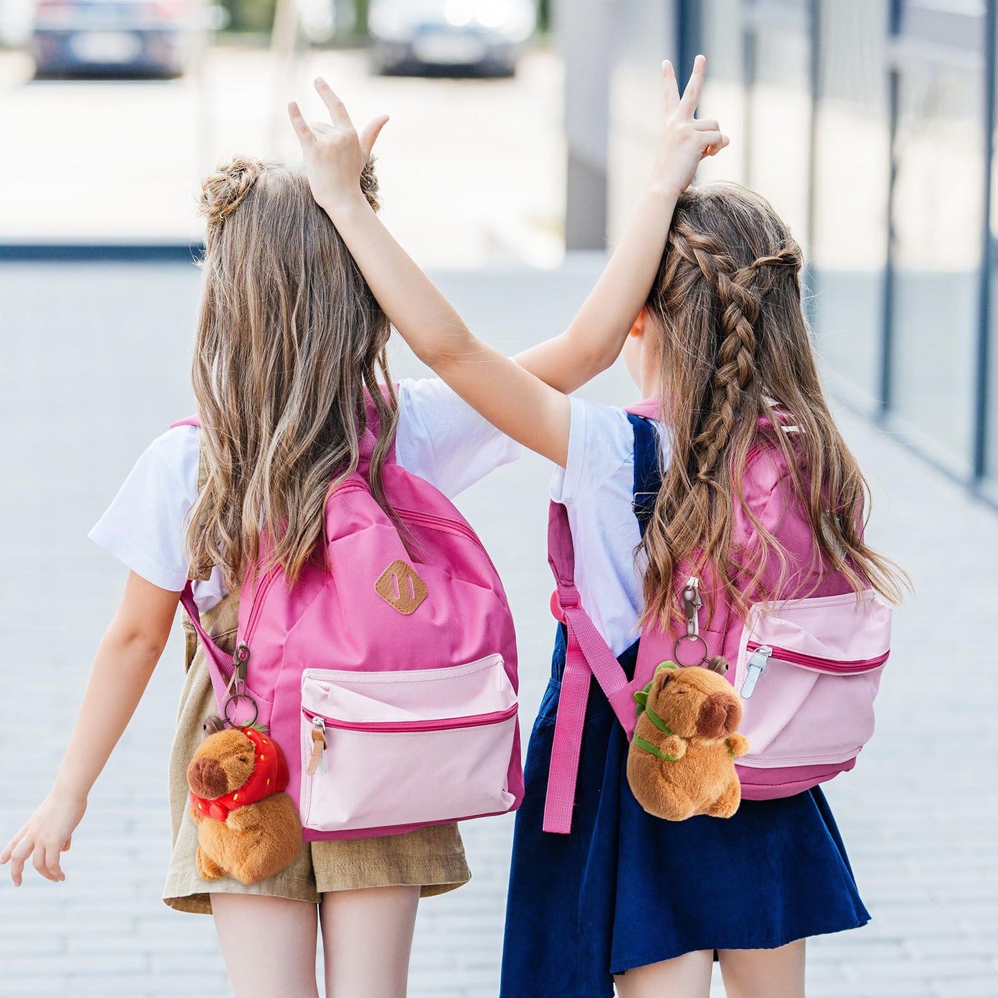 Two girls with pink backpacks featuring capybara plush keychain with turtle bag walking outdoors