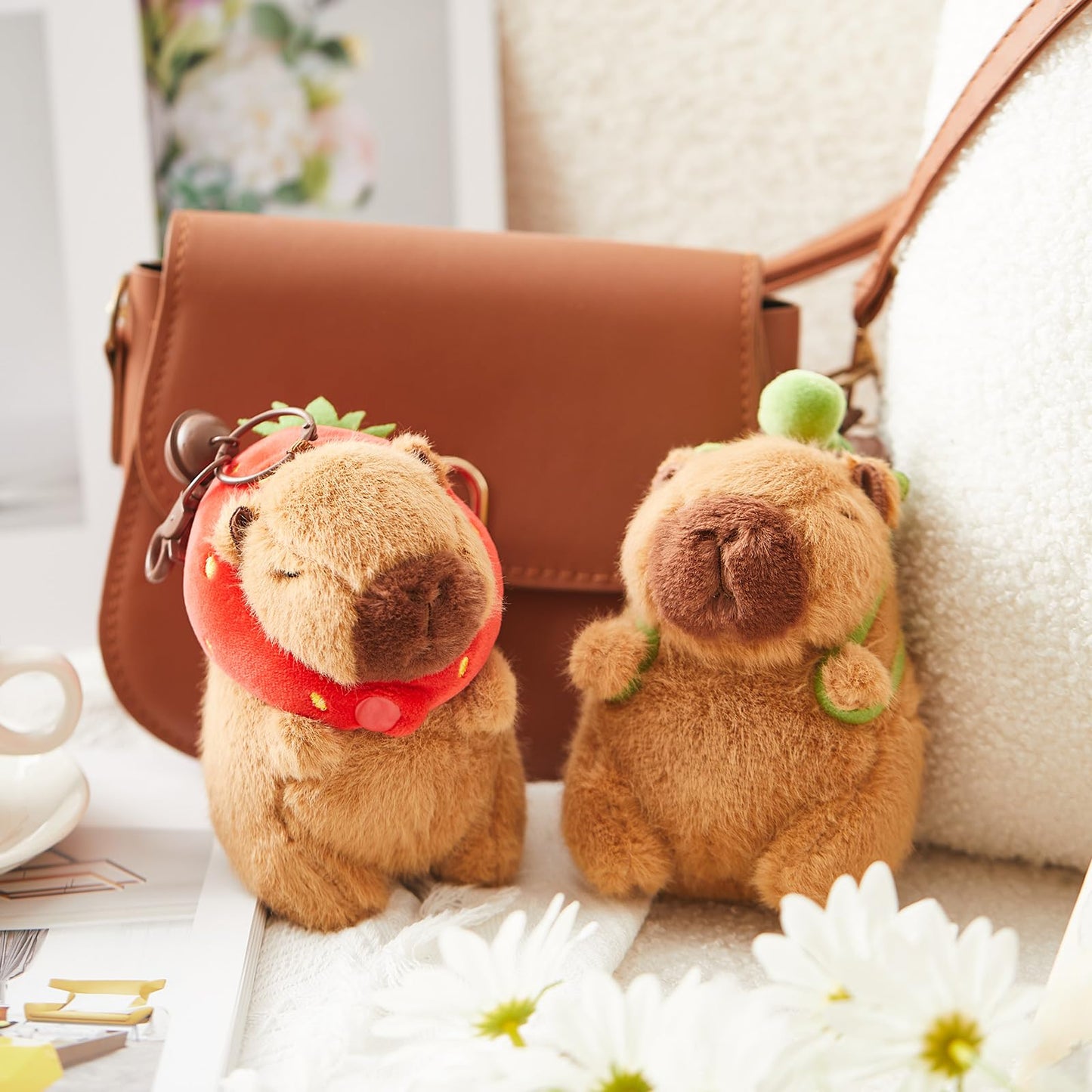 Capybara plush keychain with turtle bag decoration attached to brown bag in cozy setting