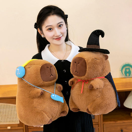 capybara plush with headset featuring blue headphones and fish pendant on brown stuffed animal