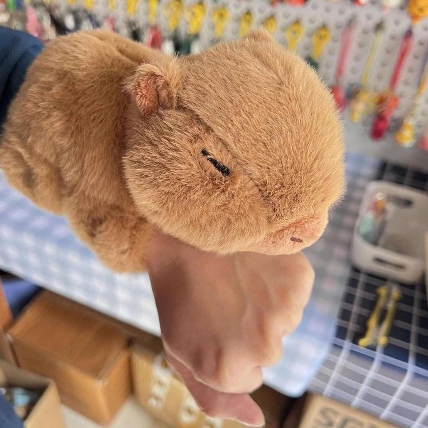 World capybara slap bracelet plush toy wrapped around wrist in indoor setting
