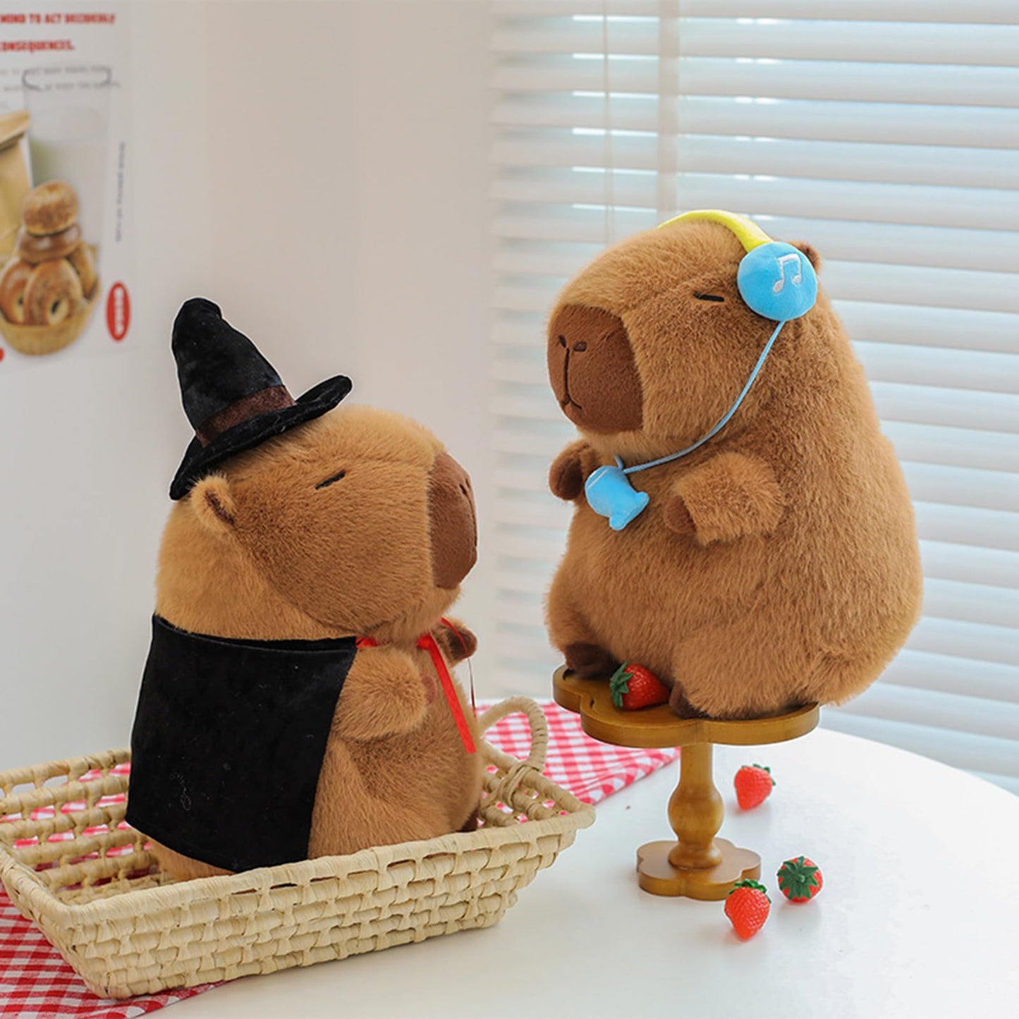 Cute wizard capybara plush wearing black hat and cape next to another capybara plush with blue headphones