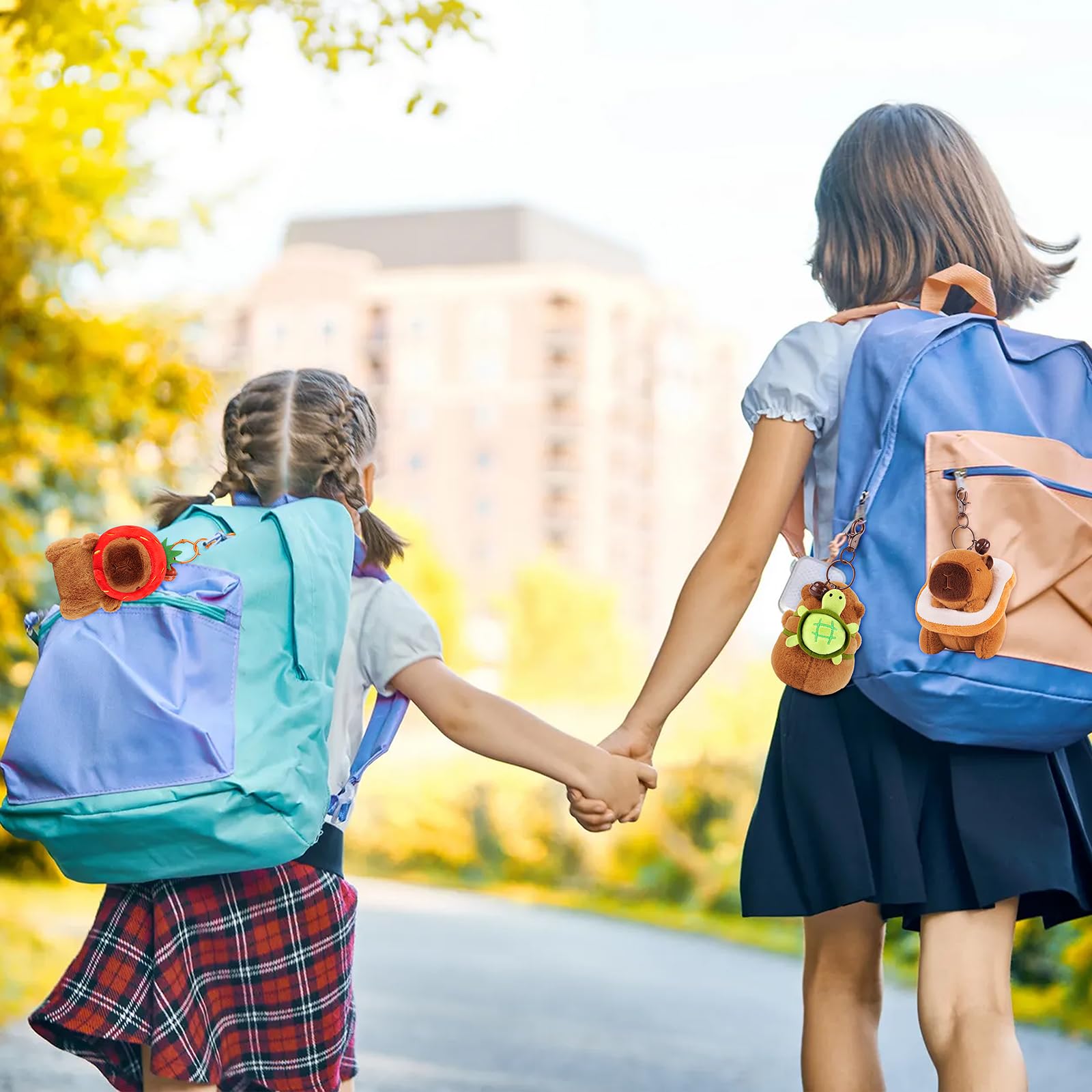Two girls holding hands walking outdoors with backpacks featuring Achwishap capybara keychain set
