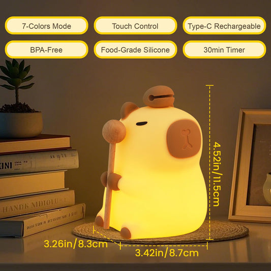 capybara night light glowing warmly while holding a wooden stick on a soft flower cushion
