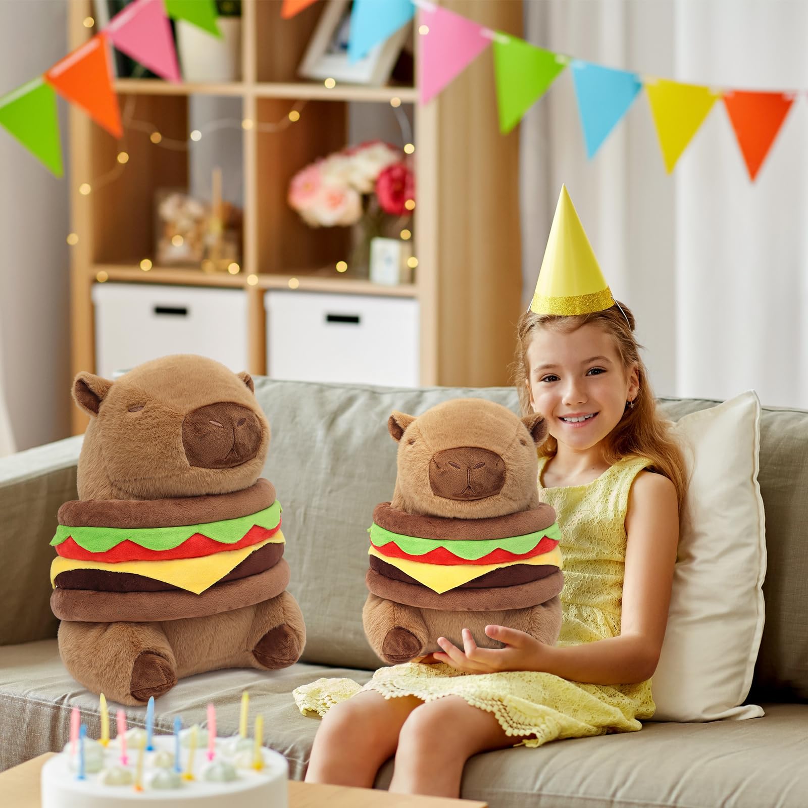 Girl holding capybara plush burger pillow while sitting next to a larger one on a couch at a birthday party