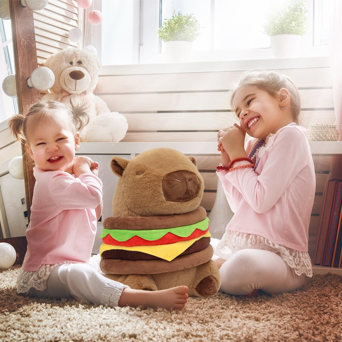 Two smiling girls sitting with a Ponjauk capybara plush burger pillow in a bright cozy room