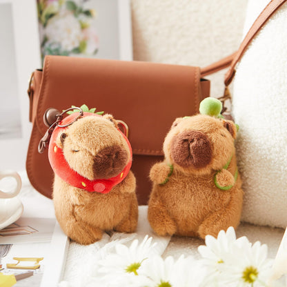 Capybara plush keychain with turtle bag decoration attached to brown bag in cozy setting