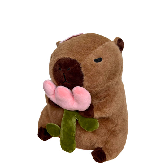 capybara plush with rose holding a pink flower with green stem and leaves