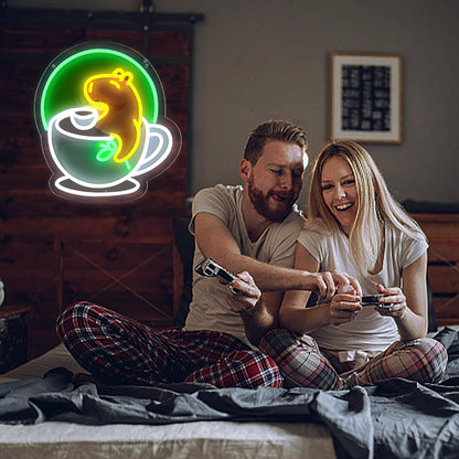Couple playing video games on bed with WittyRhE cute animal neon wall decor shaped like a yellow animal in a teacup