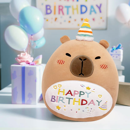 Cute capybara plush pillow wearing a party hat with happy birthday embroidery on a table